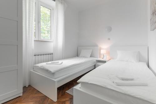 2 Betten in einem weißen Zimmer mit Fenster in der Unterkunft City Center Pearl 2 in Zagreb