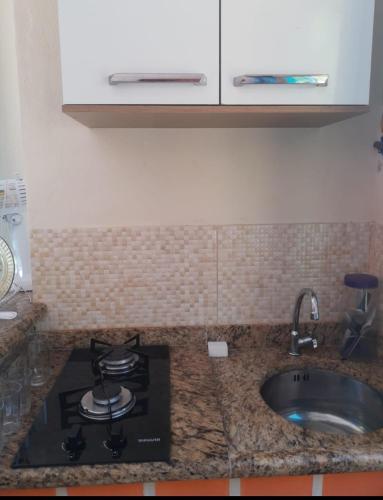 a kitchen counter with a stove and a sink at Flat do Léo in Praia de Araçatiba