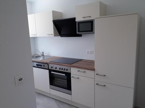 a white kitchen with a stove and a microwave at Appartements Bleistattblick in Steindorf am Ossiacher See