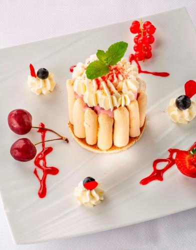 a dessert on a white plate with fruit and berries at Le Bailliage Hôtel & Spa in Salers