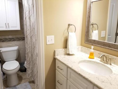 Un baño con lavabo, inodoro y espejo. en Summerhouse 101 Condo, en St. Augustine