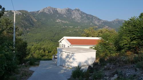 a small white building with a mountain in the background at Yokana Villa & Pool in Virpazar