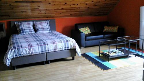 ein Schlafzimmer mit einem Bett und einem Sofa in der Unterkunft en gaume séjour au calme in Jamoigne
