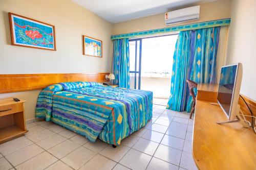 a bedroom with a bed and a desk and a television at Sol Praia Ayambra in Natal