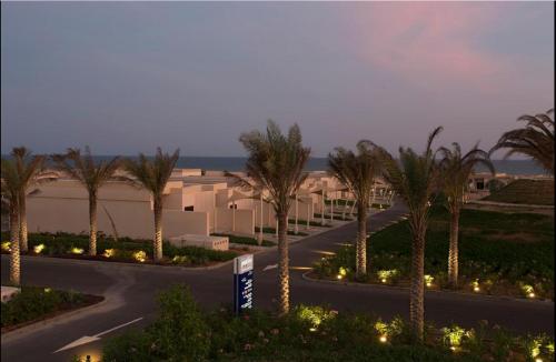 a winding road with palm trees in front of a building at Park Inn by Radisson Hotel and Residence Duqm in Duqm