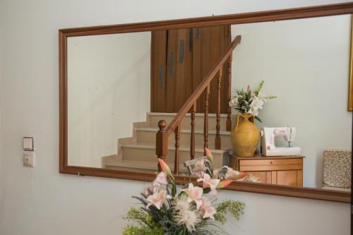 a mirror on a wall with a staircase and a vase with flowers at J&B Countryside Life - Just for two in Ágios Matthaíos