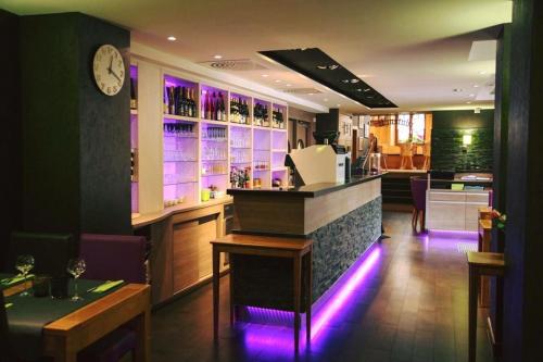 a restaurant with a bar with purple lights at Appartements Le Hupsa Pfannala in Saint-Hippolyte