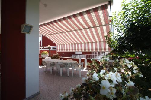 a patio with white tables and chairs and flowers at Villa della Tartaruga in Casal Palocco