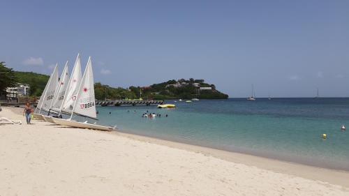 a sail boat on a beach with people in the water at akate in Les Trois-Îlets