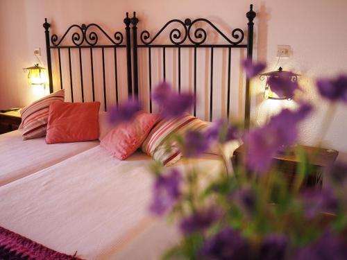 a bedroom with a bed with pillows and purple flowers at Hospedium Hostal Almanzor in Navarredonda de Gredos