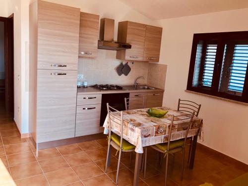 cocina con mesa y algunas sillas y cocina con fogones en Siniscola Casa vacanze Olmo, en Siniscola