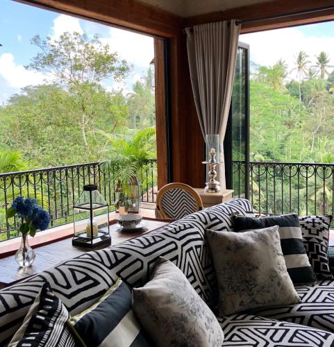 a living room with a couch and a balcony at Puri Kasih Gottlieb in Ubud