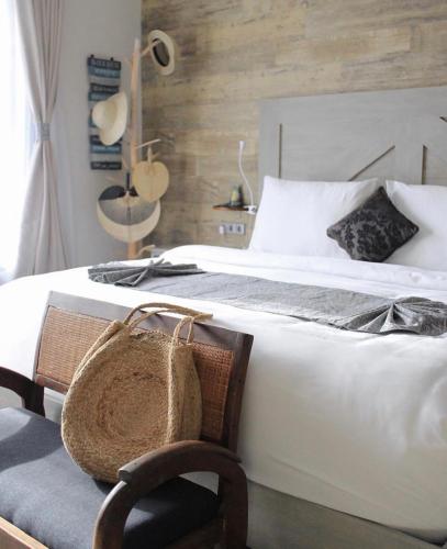 a bedroom with a large white bed with a chair at Puri Kasih Gottlieb in Ubud