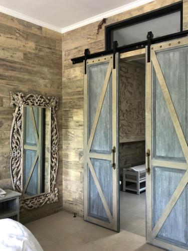 an open barn door in a bedroom with two mirrors at Puri Kasih Gottlieb in Ubud