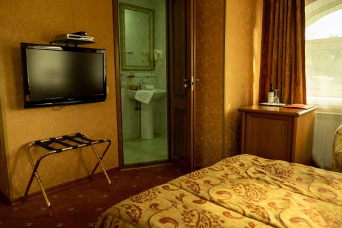 a hotel room with a bed and a flat screen tv at Diplomat Club Hotel in Chişinău