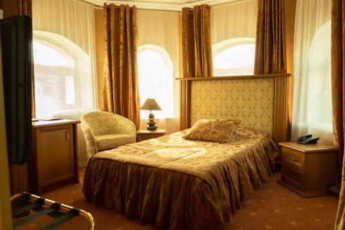 a bedroom with a bed and a chair and windows at Diplomat Club Hotel in Chişinău