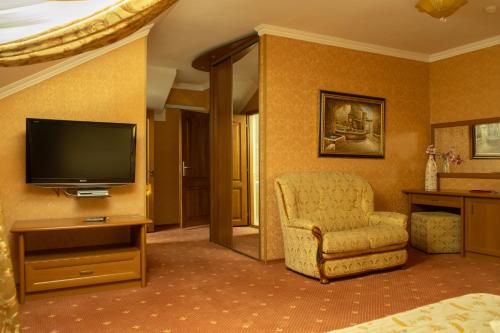 a hotel room with a tv and a chair and a television at Diplomat Club Hotel in Chişinău