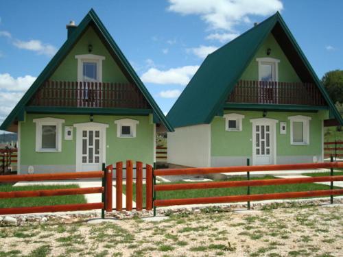 a green house with a fence in front of it at Rooms and Bungalows Sreten Žugić in Žabljak