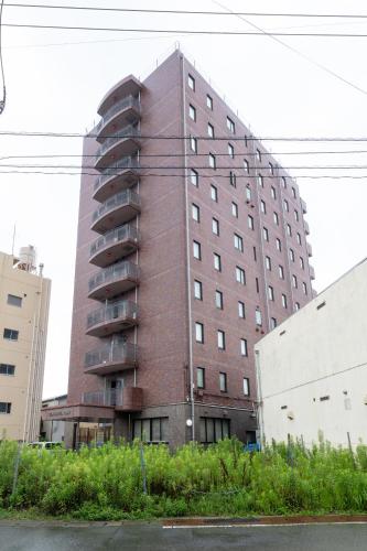 a tall red brick building in a city at Sun Hotel Tosu Saga in Tosu