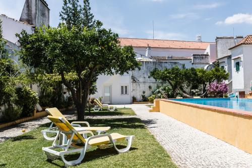 - un groupe de chaises assises sur l'herbe près d'une piscine dans l'établissement Vintage Guest House - Casa do Escritor, à Évora