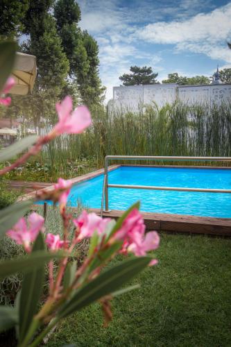 a swimming pool with pink flowers in front of it at Renegade Hotel in Siófok