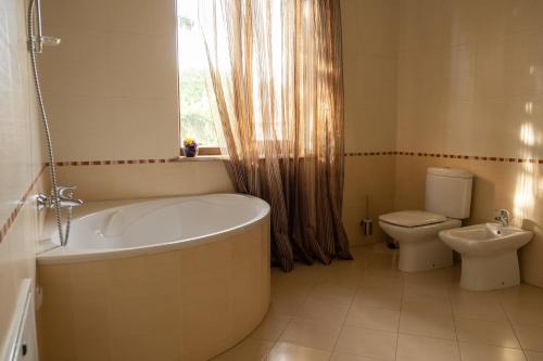 a bathroom with a tub and a toilet and a window at Diplomat Club Hotel in Chişinău