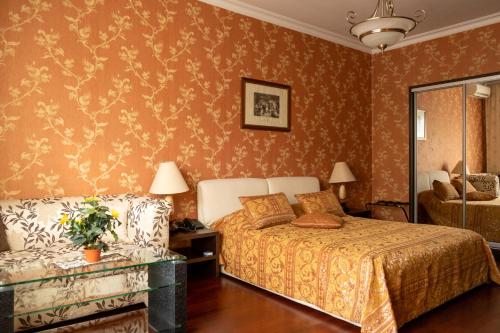 a bedroom with a bed and a couch and a mirror at Diplomat Club Hotel in Chişinău