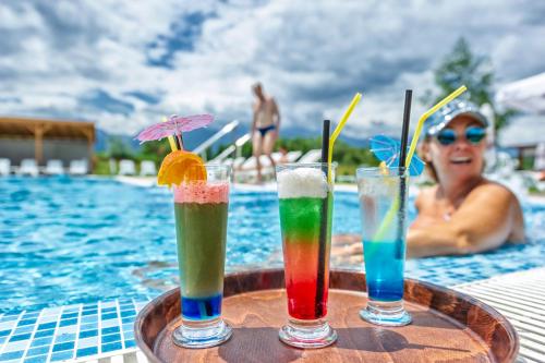 three drinks on a tray next to a swimming pool at Thermal Hotel Seven Seasons in Banya
