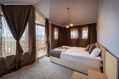 a bedroom with a bed and large windows at Thermal Hotel Seven Seasons in Banya