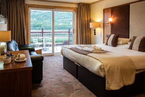 a hotel room with a large bed and a balcony at Cairndow Stagecoach Inn in Cairndow