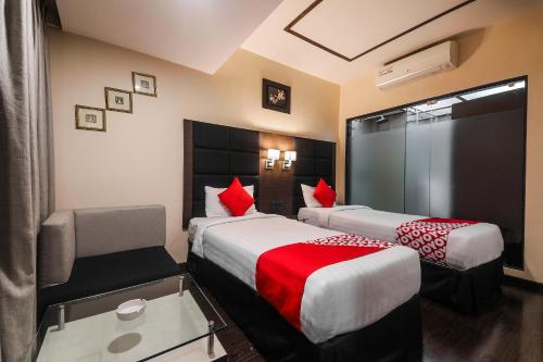 a hotel room with two beds with red pillows at Alpine Continental in Shillong