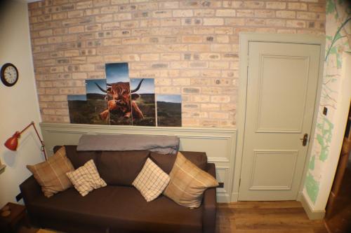 a living room with a couch and a brick wall at The Victoria Inn Blythswood Snug in Falkirk