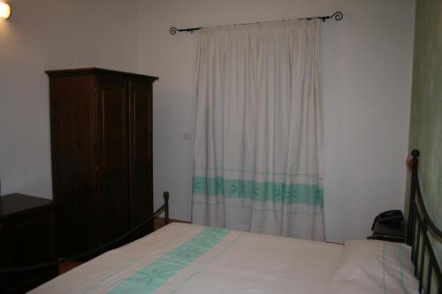 a bedroom with a bed and a dresser and a window at La Fattoria in Castelsardo