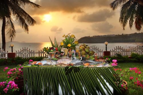 a table with food and flowers on it with the ocean at Bogmallo Beach Resort in Bogmolo