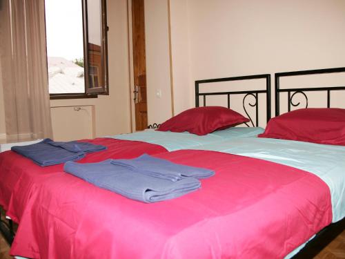 a bed with red pillows and blue towels on it at Two Towers Guest House in Kutaisi