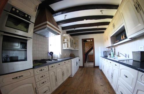 a large kitchen with white cabinets and black counter tops at Domaine des grandes landes in Saint-Paul-la-Roche