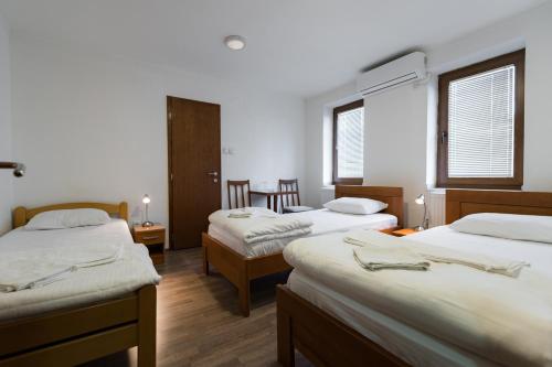 a room with three beds and two chairs in it at Rooms Gat in Subotica
