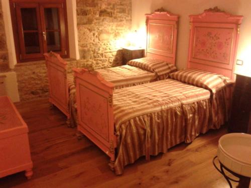 a bedroom with two beds and a stone wall at Alloggio Agrituristico Conte Ottelio in Pradamano