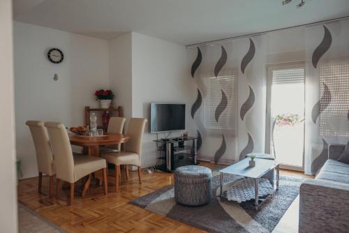 een woonkamer met een tafel en stoelen en een televisie bij Apartman "JOKA" in Ðakovo