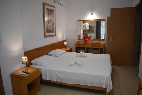 a bedroom with a white bed and a dining room at Hotel Ritsa in Kamena Vourla