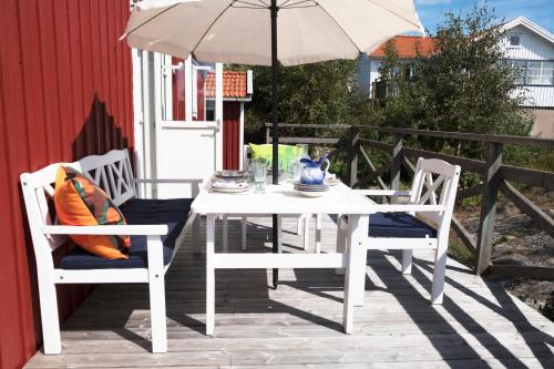 a white table and chairs with an umbrella on a patio at Kvarnstugan in Mollösund