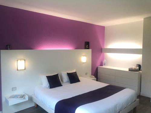 a bedroom with a large bed with purple walls at Logis Latitude Ouest Hôtel Restaurant & Spa in Locronan