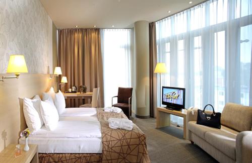 Pokój hotelowy z łóżkiem, kanapą i telewizorem w obiekcie Rixwell Elefant Hotel w Rydze
