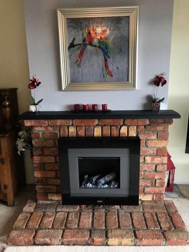 a brick fireplace with a painting on the wall at Lighthouse Cottage in Donegal