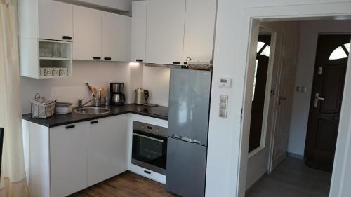 a kitchen with white cabinets and a stainless steel refrigerator at Domek Gościnny Dyziówka in Szczyrk
