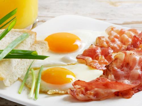 a white plate with eggs and bacon and toast at Mishol Bodas Hotel & Beach Club Acapulco Diamante in Acapulco