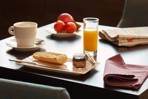 une table avec une assiette de nourriture et un verre de jus d'orange dans l'établissement Ashley Hôtel Le Mans Centre Gare, au Mans
