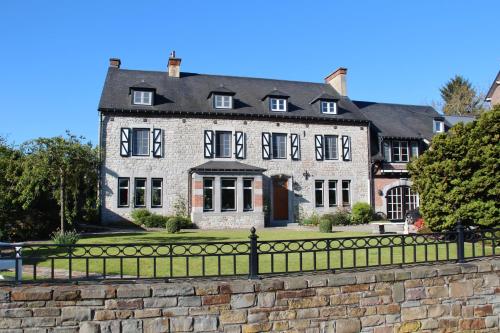 a large stone house with a black fence at Le Pré-Chet in Profondeville