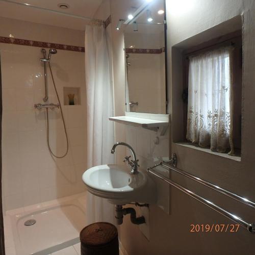 une salle de bain blanche avec un lavabo et une douche dans l'établissement La Pierre qui Parle, à Luynes