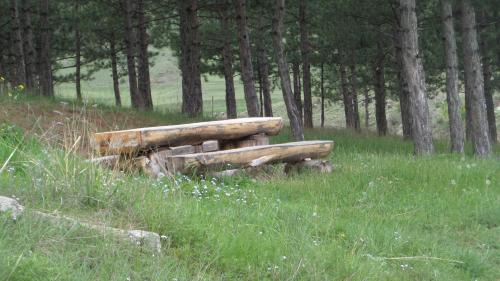 a wooden bench sitting in the middle of a field at Wooden house ,,Tsunda" in Vardzia
